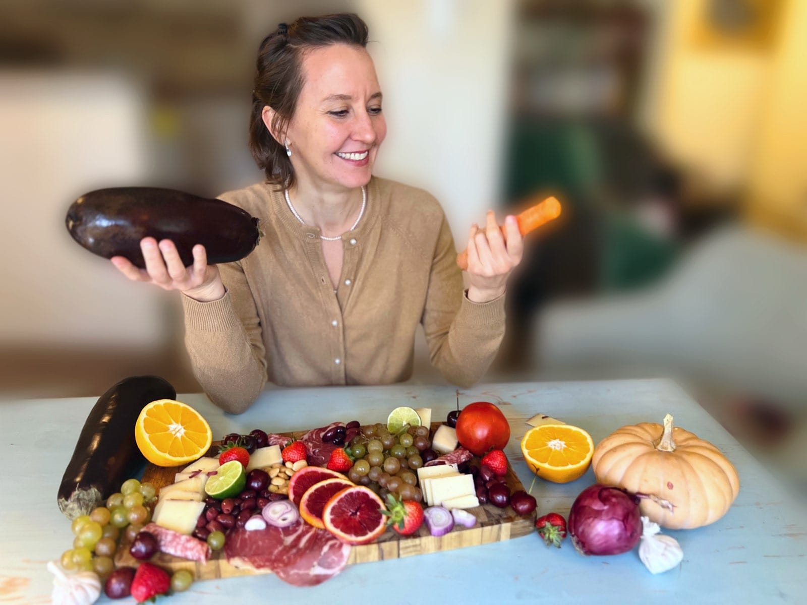 Alexia Valdes holding fresh vegetables with a colorful food board
